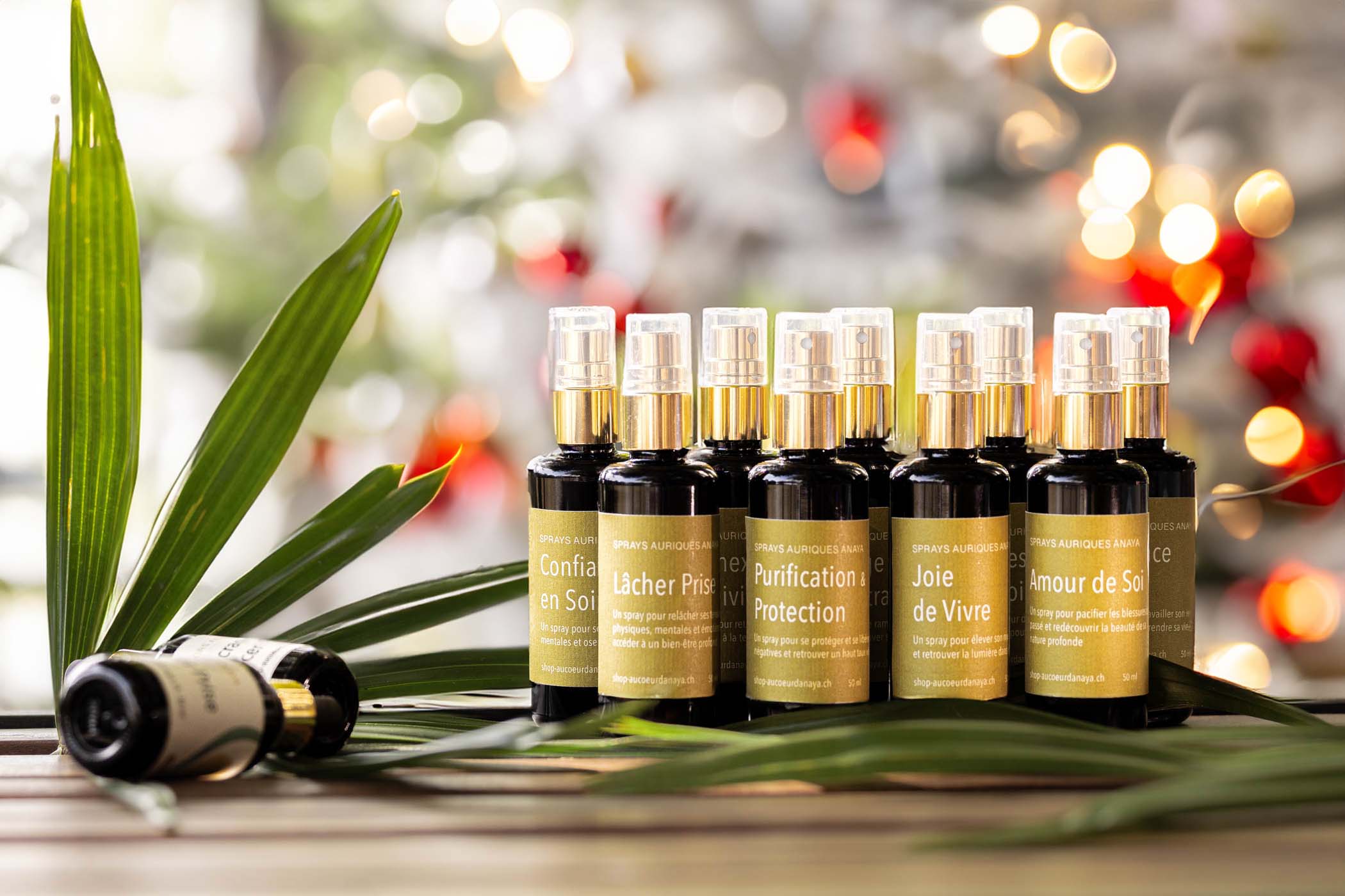 spray aurique produit bien être spray purification protection posé sur table avec branche de palmier en premier fond et sapin de noël en arrière fond noël